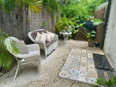 a patio with two chairs and a couch and a table at Flora's Garden Apartment/Studio in North Miami