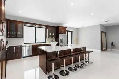 a kitchen with wooden cabinets and a island with bar stools at Granada Modern Luxury in Massive Mansion with Heated Pool in Miami