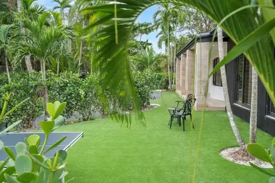 a garden with green grass and two chairs on it at VillaKoBo Heated Pool Spa Bar Tennis Golf in Miami