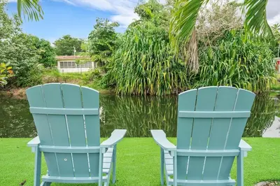 two blue chairs sitting on the grass next to a lake at VillaKoBo Heated Pool Spa Bar Tennis Golf in Miami