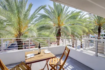 a balcony with a table and chairs and palm trees at Miami Beach Vacation Rental with Rooftop Pool Access in Miami Beach