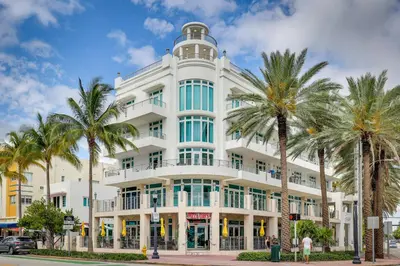 a white building with palm trees in front of it at Miami Beach Vacation Rental with Rooftop Pool Access in Miami Beach
