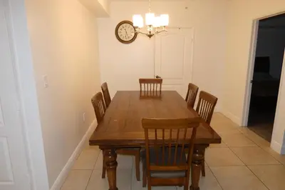 a dining room table with chairs and a clock on the wall at 3BR Condo in Sunny Isles Beach in Miami Beach