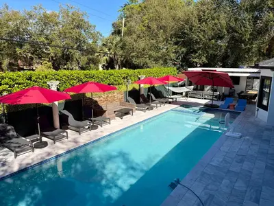 a swimming pool with umbrellas and chairs and tables at VillaLee Luxury Heated Pool & Spa Sauna Golf in North Miami