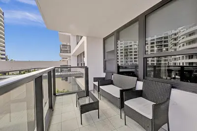 a balcony with chairs and a view of a building at Modern Miami Beach Condo with Beach Service & Pool in Miami Beach