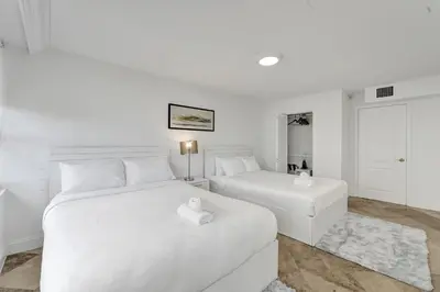 two beds in a room with white walls and white furniture at Modern Miami Beach Condo with Beach Service & Pool in Miami Beach