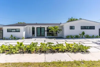 a white house with plants in front of it at Heated Pool Modern 5 Bedrooms House 10 minutes to the Ocean in Miami