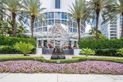 a sculpture in front of a building with palm trees at TRUMP INTERNATIONAL BEACH RESORT 2 BEDROOM APARTMENT 1600 Sqf Ocean and Bay View in Miami Beach