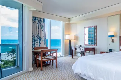 a hotel room with a bed and a desk and a window at TRUMP INTERNATIONAL BEACH RESORT 2 BEDROOM APARTMENT 1600 Sqf Ocean and Bay View in Miami Beach