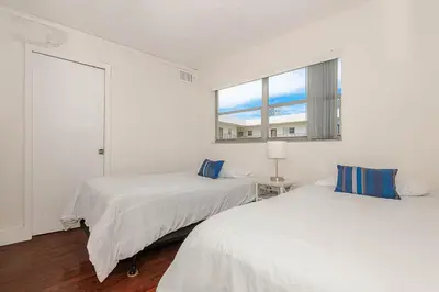 two beds in a white room with a window at Amazing condo 5 minute walk to the beach! in Miami Beach
