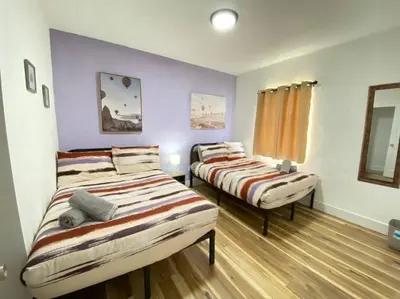 two beds in a room with purple walls and wooden floors at Heart of Miami sleeps 10 near Little Havana Beaches in Miami