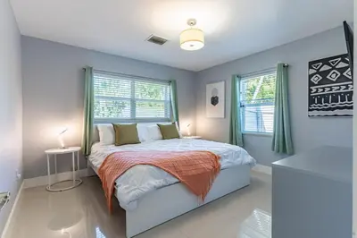 a bedroom with a bed and two windows at Villa Aura Heated Pool 4 Bedrooms 5 minutes to the Ocean in Fort Lauderdale