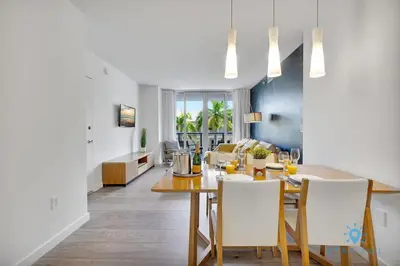 a dining room and living room with a table and chairs at Pool Apartment with Balcony Near Beach in Hallandale Beach