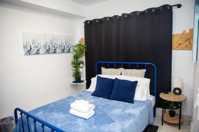 a bedroom with a blue bed and a black curtain at Insta Worthy Oasis in Homestead