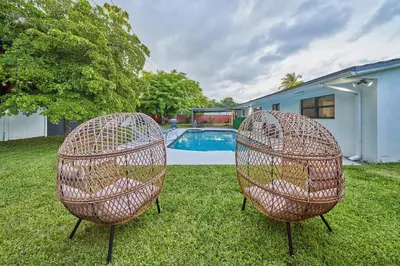 two wicker chairs sitting in the grass near a pool at Top Location Villa at Highland Lakes Blvd BY THE GLAMHOMES in Miami