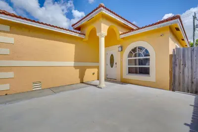 a yellow house with a white door and a fence at Stylish Fort Lauderdale Home 5 Mi to Beach! in Fort Lauderdale