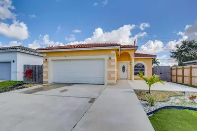 a small yellow house with a garage at Stylish Fort Lauderdale Home 5 Mi to Beach! in Fort Lauderdale