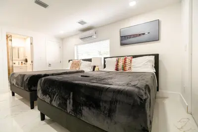 a bedroom with two beds and a tv on the wall at Amazing Villa at Highland Lakes Boulevard BY THE GLAMHOMES in Miami