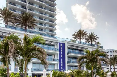 an apartment building with palm trees in front of it at Churchill Suites Monte Carlo Miami Beach in Miami Beach