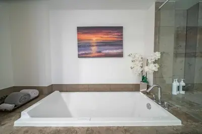 a white bath tub in a bathroom with a painting at Luxury Ocean View 2BR Corner Unit at W residence in Miami