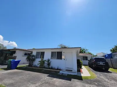 a white house with a car parked in a driveway at Sol Miami #1 with free parking on premises in Miami