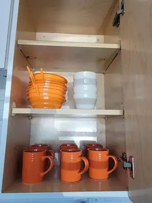 a cupboard filled with orange cups and bowls at Sol Miami #1 with free parking on premises in Miami