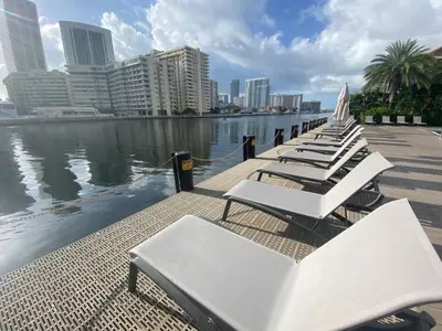 a row of white lounge chairs next to the water at Elegant Coastal Living, Full Kitchen & Panoramic Views -A in Hallandale Beach