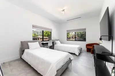 a white bedroom with two beds and a television at Super Modern Waterfront Paradise Near the Beach in Miami