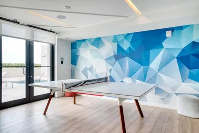 a ping pong table in a room with a blue wall at Coral Gables 1br w pool wd nr shops airport MIA-74 in Miami