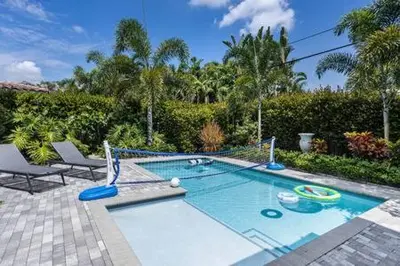a swimming pool in a yard with two chairs at VILLA MAGNOLIA-with heated pool-by VIAC in Fort Lauderdale
