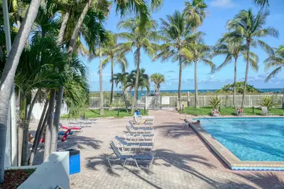 a pool with chaise lounge chairs and palm trees at Deluxe Studios and Apartments at the Casablanca in Miami Beach