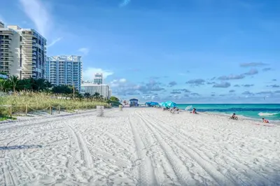 a beach with people on it with buildings and the ocean at Deluxe Studios and Apartments at the Casablanca in Miami Beach