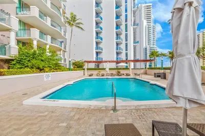 a swimming pool with an umbrella next to a building at King David By The Ocean in Miami Beach