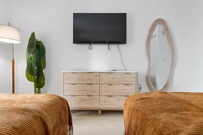 a room with two beds and a tv and a mirror at King David By The Ocean in Miami Beach