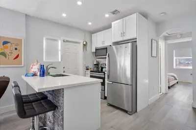 a kitchen with white cabinets and a stainless steel refrigerator at Massage Chair - Backyard - 5 min 2 DT Calle 8 Brickell in Miami
