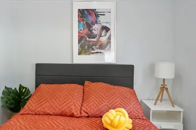 a bed with a orange comforter with a yellow pillow on it at Massage Chair - Backyard - 5 min 2 DT Calle 8 Brickell in Miami