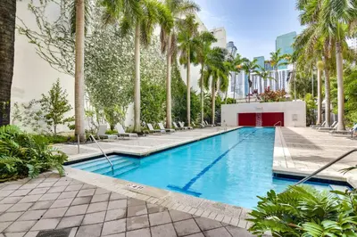 a swimming pool with palm trees in a resort at Trendy Downtown Miami Studio Pools, Views and More! in Miami
