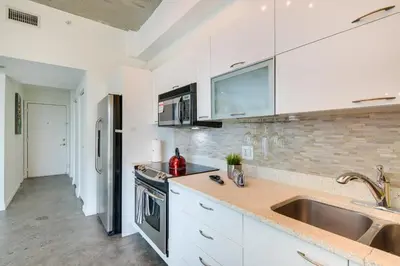 a kitchen with white cabinets and a sink at Trendy Downtown Miami Studio Pools, Views and More! in Miami