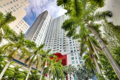 a tall building with palm trees in front of it at Trendy Downtown Miami Studio Pools, Views and More! in Miami
