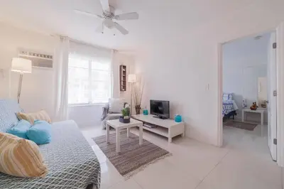 a white living room with a couch and a tv at OCEAN & SAND ONLY 1 MINUTE WALK! in Miami Beach