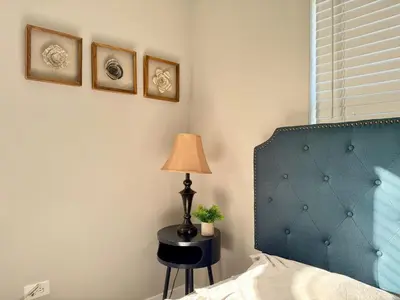 a bedroom with a blue headboard and a table with a lamp at HOT TUB HOUSE ON GOLF COURSE! 10 MINs TO THE BEACH in Miami