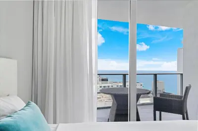 a bedroom with a bed and a balcony with a table at Stay on the beach-16th Floor Views Pool Gym in Hallandale Beach