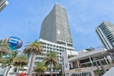 a tall building with palm trees in front of it at Stay on the beach-16th Floor Views Pool Gym in Hallandale Beach