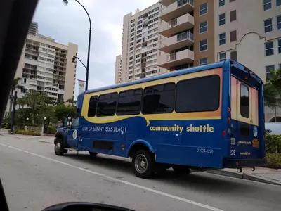 a blue and yellow bus driving down the street at Estudios para 4 personas en la playa de Sunny Isles Beach in Miami Beach