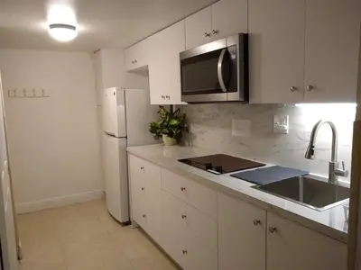 a kitchen with white cabinets and a stainless steel refrigerator at Estudios para 4 personas en la playa de Sunny Isles Beach in Miami Beach