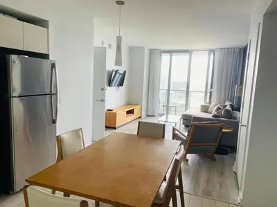 a kitchen and living room with a table and a refrigerator at Refined Oceanview Apartment, Kitchen, Comfort & Location -A in Hallandale Beach