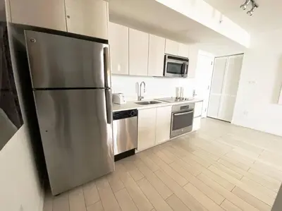a large kitchen with a stainless steel refrigerator at Contemporary Beach Retreat, Sleek Design & Full Kitchen -A in Hallandale Beach