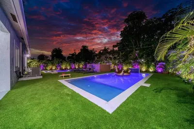 a backyard with a swimming pool and green grass at Luxury Duplex in Heart of Fort Lauderdale Near The Beach in Fort Lauderdale