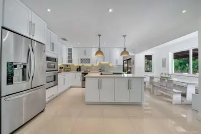 a large kitchen with white cabinets and stainless steel appliances at Luxury 7BR Villa Vizcaya Pool Sauna Gym Golf in Miami
