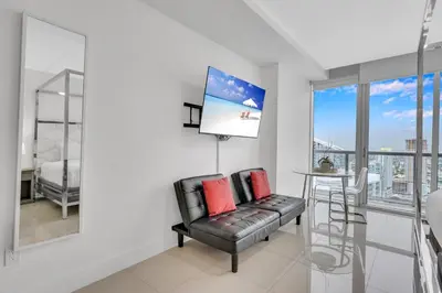 a living room with a black leather chair and a table at Highest floor Icon W Brickell Location in Miami